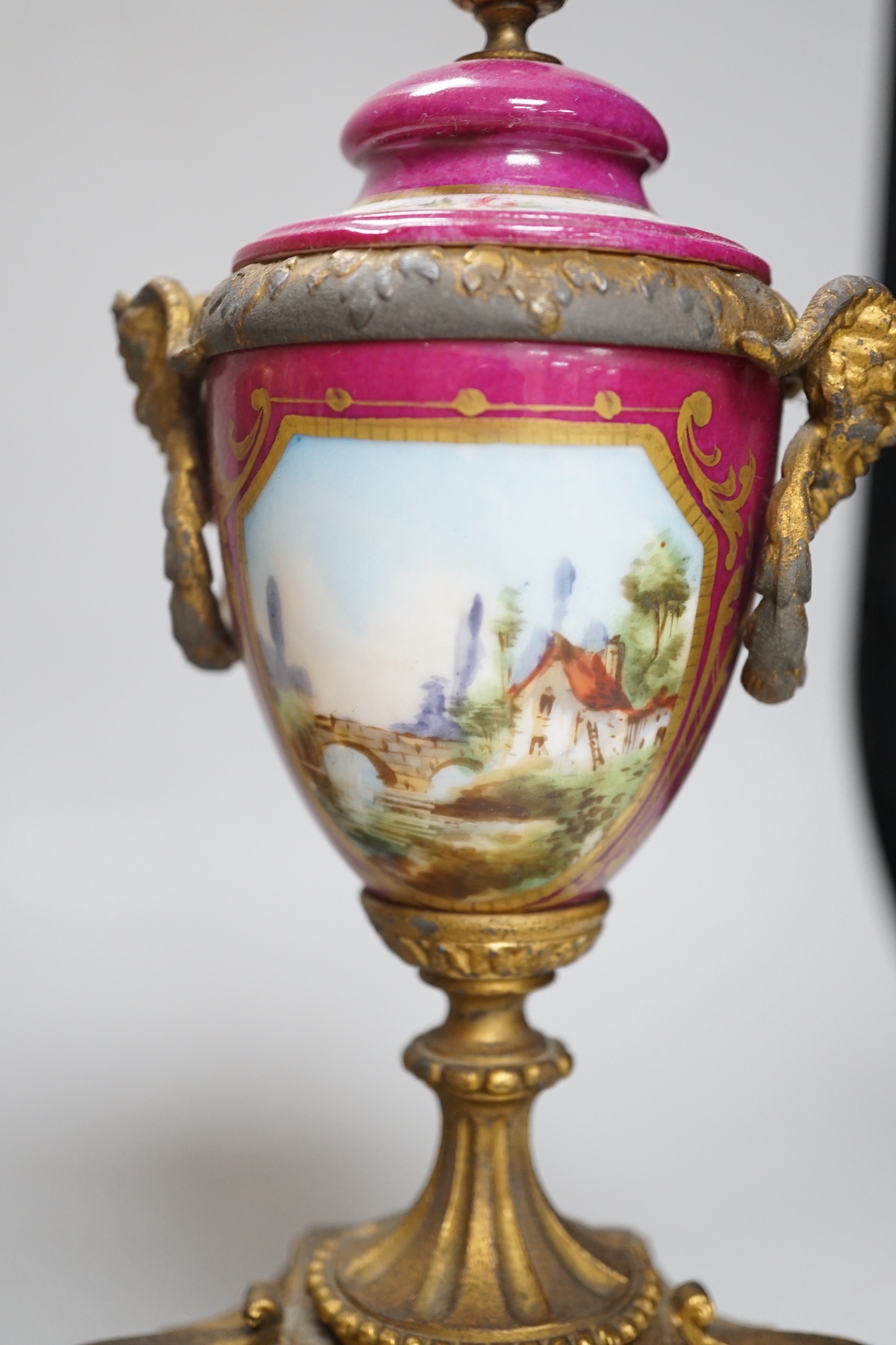 A 19th century porcelain mounted gilt spelter clock garniture, hand painted with landscapes, 30cm high